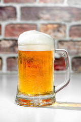 Refreshing beer mug with foam on a white bar