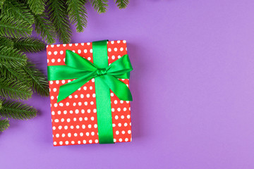 Top view of gift box and fir tree branches on colorful background. Merry Christmas concept with empty space for your design