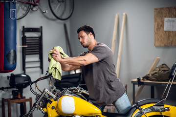 Fototapeta na wymiar A strong male biker repairs his motorcycle in the garage. Interior of the workshop.