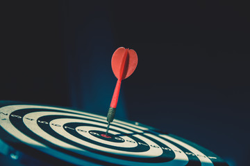 Bullseye or dart board has dart arrow throw hitting the center of a shooting target for business...