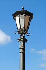 Fototapeta na wymiar Isolated Ornate Black Iron Lantern on Street Light against Blue Sky 