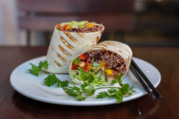 Vegan burrito. Sliced up raw food wrap with vegan ingredients on a plate
