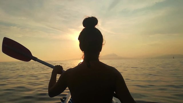 una giovane donna in canoa. mare al tramonto. Turismo, estate, tramonto, libert&agrave;.