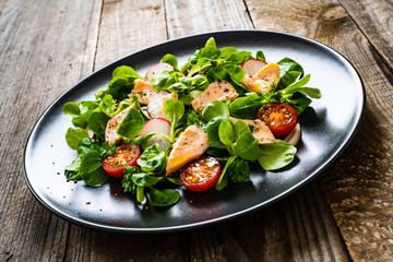 Salmon salad - roasted salmon and vegetables on wooden background
