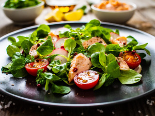 Salmon salad - roasted salmon and vegetables on wooden background

