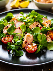 Salmon salad - roasted salmon and vegetables on wooden background
