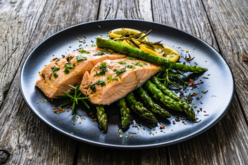 Roasted salmon steaks with  asparagus and lemon on wooden table
