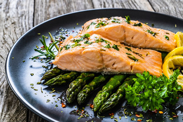 Roasted salmon steaks with  asparagus and lemon on wooden table
