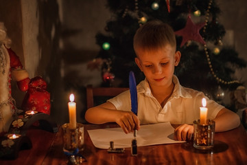 a boy of European appearance holds a blue feather in his hands and dips in ink