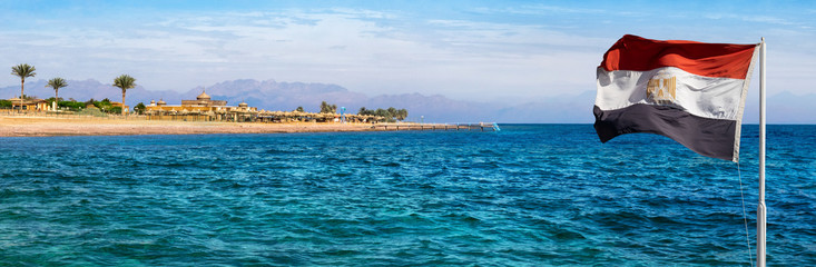 Aqaba bay view near the Dahab resort with a hotel, palms and silhouettes of mountains at skyline....