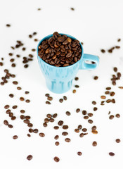 Coffee beans inside blue cup on white background