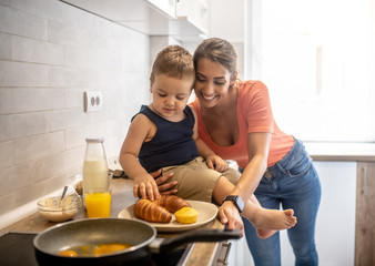 Mother and son spend time together in the kitchen, make breakfast and smile