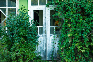 Fototapeta na wymiar Facade of abandoned house. Old wooden door. Old wall with big vintage gates
