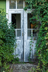 Facade of abandoned house. Old wooden door. Old wall with big vintage gates