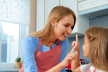 Beautiful mother and her adorable daughter having fun in the kitchen while cooking food