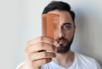 Male hand holding beard comb