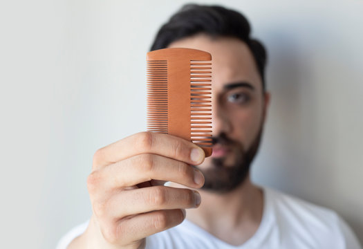 Male hand holding beard comb