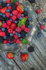 Raspberries, strawberries, blackberries, blueberries in a plate on a wooden background