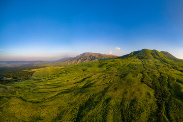 阿蘇山の北側から往生岳を中心に真夏の緑の山肌をドローン空撮した風景が雄大で美しい。