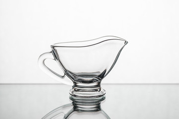 Empty clear glass gravy boat isolated on a white background