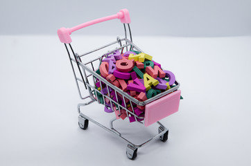 Multicolored wooden letters in a metal supermarket trolley on a white background. Concept: back to...
