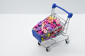 Multicolored wooden numbers in a metal supermarket trolley on a white background. Concept: back to...