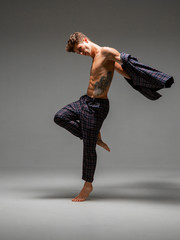 Handsome young man actor dancer in suit dancing barefoot modern expressive dance in studio isolated...