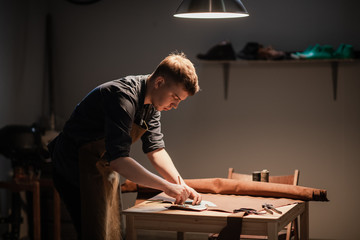 a young apprentice makes blanks for the production of shoes in the workshop.