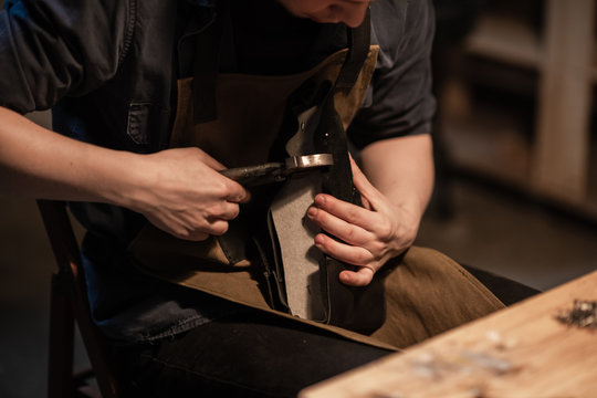 a young shoemaker in a Shoe shop makes shoes from leather with his own hands.