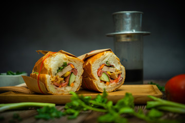 Snack at break time. Famous Vietnamese food is Banh mi thit and black coffee, popular street food from bread stuffed with raw material: pork, ham, pate, egg and fresh herbs.Typical Vietnamese sandwich