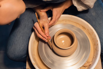 close-up of the hands of a Potter when sculpting a vase from clay on a Potter's wheel in the workshop.