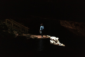 Entrance to the karst cave in a mountain. Natural cave opening. Inside the subterranean cave background with copy space. Dark cave with a bright daylight spot of exit.