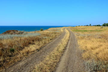 Fototapeta na wymiar Country field road ruts along the sea.