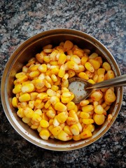 Yellow Corn seeds with chilly powder mixed in a steel bowl. 