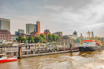 Busy port with many old and modern sailing boats and ships in Hamburg harbor during warm sunset, Germany