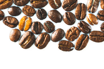 Roasted coffee beans on white milk background. Coffee beans in milk. Top view macro shot of arabica, robusta and iberica coffee seeds. 