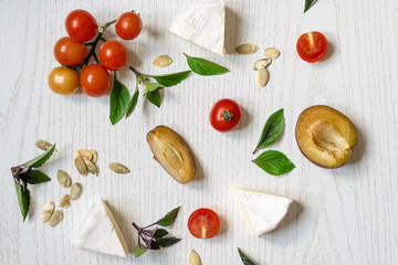 Charcuterie board of assorted cheeses, vegetables and appetizers. Above Top view table scene on a white wood background.