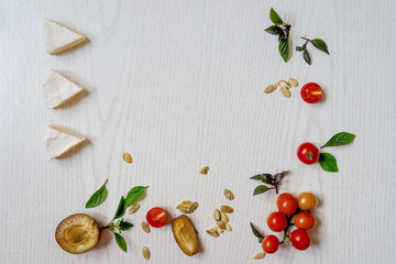 Charcuterie board of assorted cheeses, vegetables and appetizers. Above Top view table scene on a white wood background.