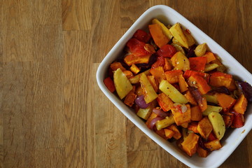 Ofengemüse in einer weißen Schale auf dem Holztisch