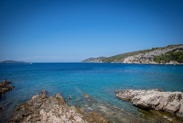 Fototapeta na wymiar Beautiful turquoise sea at Hvar island, Croatia, with steep rocky cliffs towering above the water