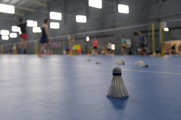 close up one badminton on indoor stadium floor. Defocused people playing badminton