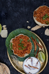Tomato rice pilaf in papad bowl on banana leaf with chilies soaked in curd, copy space
