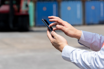Shipping officer using smart phone  at the container yard.