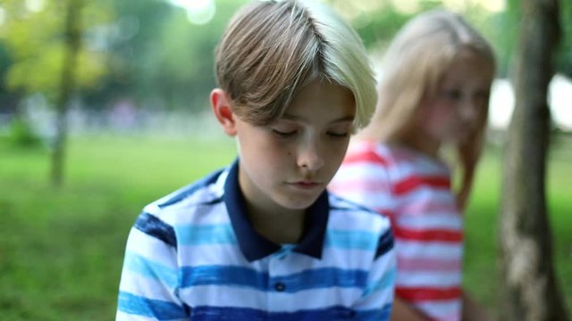 Handsome brother and sister using tablet in summer green park. Kids use laptop computer for learning online. New education system. Internet searching. Traveling family activity. Social networking.