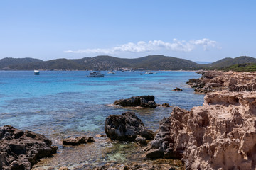 Fototapeta na wymiar View of the beautiful rocky coast turquoise sea with boats. Ibiza. Balearic Islands, Spain