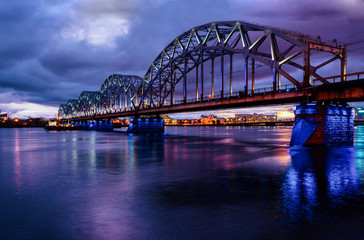 Naklejka premium Railway bridge across Daugava or Dvina river. Riga, Latvia night cityscape .