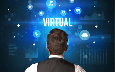 Rear view of a businessman with VIRTUAL inscription, modern technology concept