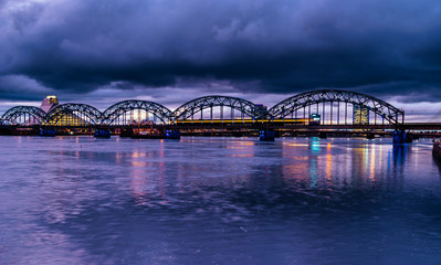 Railway bridge across Daugava or Dvina river. Riga, Latvia night cityscape .