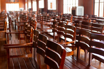 lot of wooden chairs stand in a diagonal in a large room