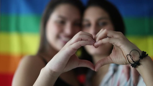 Lesbian couple doing heart symbol with hand. LGBT women together smiling and dating